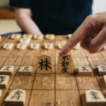 株と不動産と書かれた将棋の駒を指す指